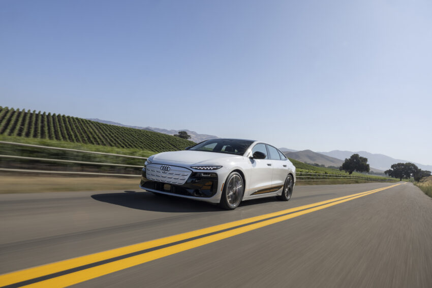Audi S6 drives on a straight road past vineyards