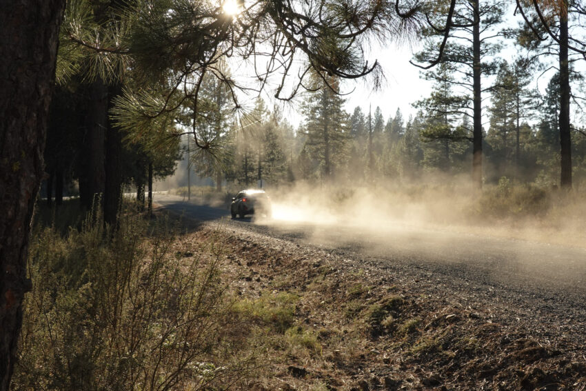 A car throws up a dust cloud on a dirt road